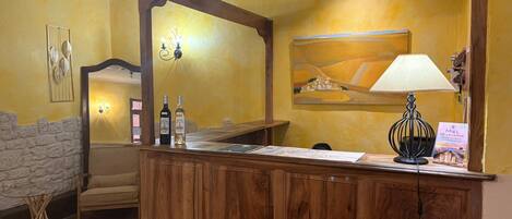 Una recepción con detalles de madera, una lámpara y dos botellas de vino.