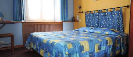 Un dormitorio con cama, escritorio y ventana con cortinas.