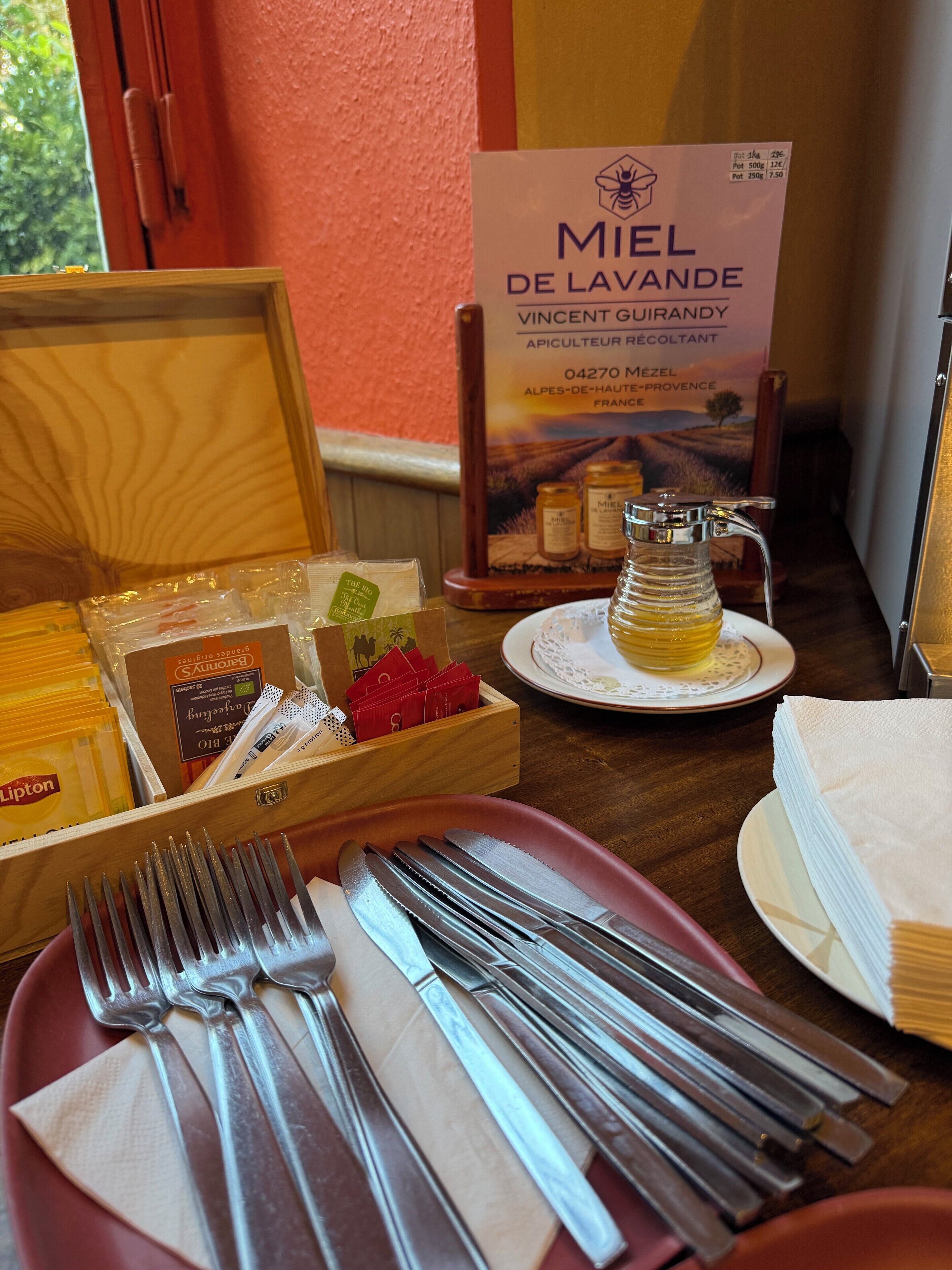 A table set with cutlery, napkins, and a bottle of Miel de Lavande.