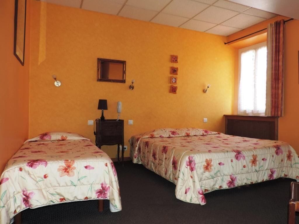 A room with two beds, a desk, a chair, a clock, and a window with curtains.