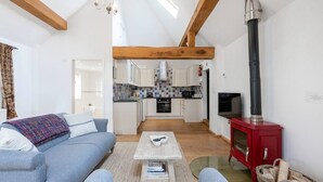 Een moderne woonkamer met een blauwe bank, een bijzettafeltje en een rode houtkachel.