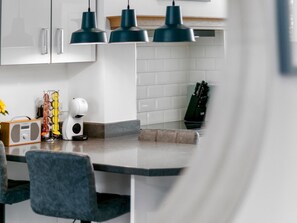 A modern kitchen with white cabinets, a grey countertop, and three black pendant lights. - Refurbished 2 Bed Close To City - Pass The Keys (York)