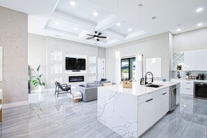 Een moderne keuken met een groot schiereiland, inbouwapparatuur en een zithoek met een bank en stoelen.