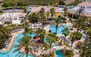 Eine Luftaufnahme eines Resorts mit mehreren Schwimmbecken, Palmen und Liegestühlen.