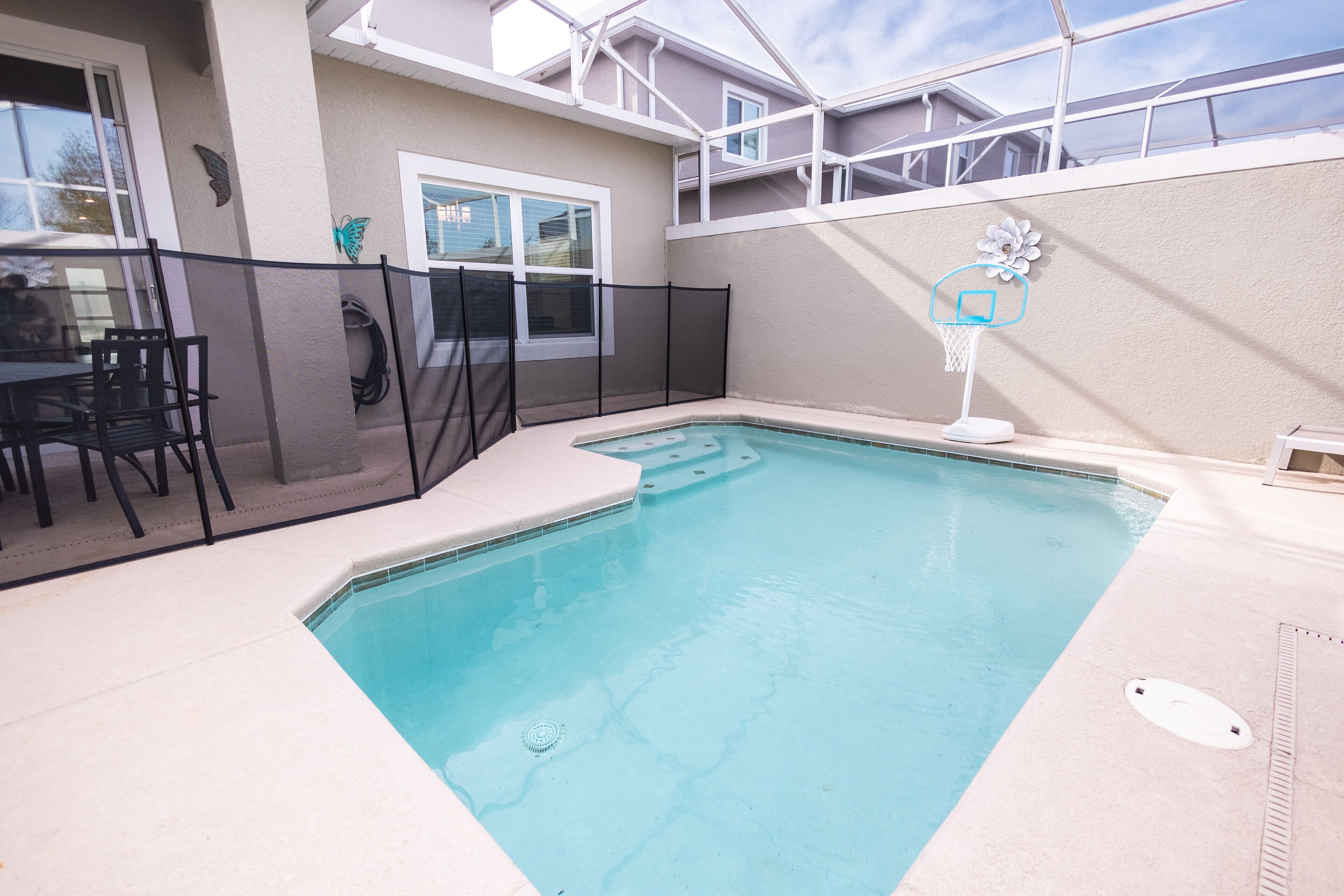A swimming pool with a diving board, a fenced patio area, and a window with a butterfly decoration.