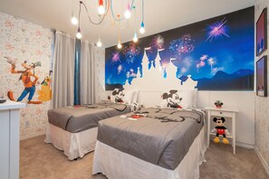 A room with two beds, a mural of animated characters, a Mickey Mouse plush toy, and a large wall painting of fireworks.