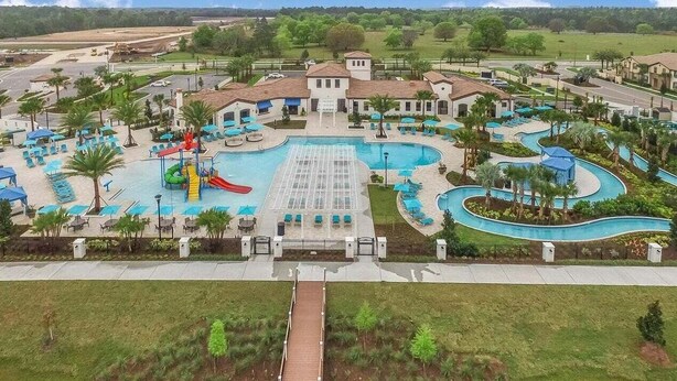 Vue aérienne d’un complexe hôtelier doté d’une piscine centrale, de plusieurs toboggans aquatiques et de divers espaces de détente.