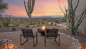 A desert garden with a fire pit, two chairs, and cacti. - Cimarron: Spectacular city and mountain views, pool, hot tub, and more! (Catalina Foothills)