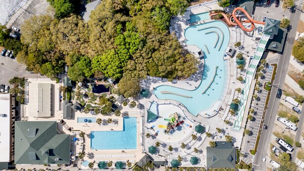 Vista aérea de um resort com várias piscinas, um toboágua e estacionamento.