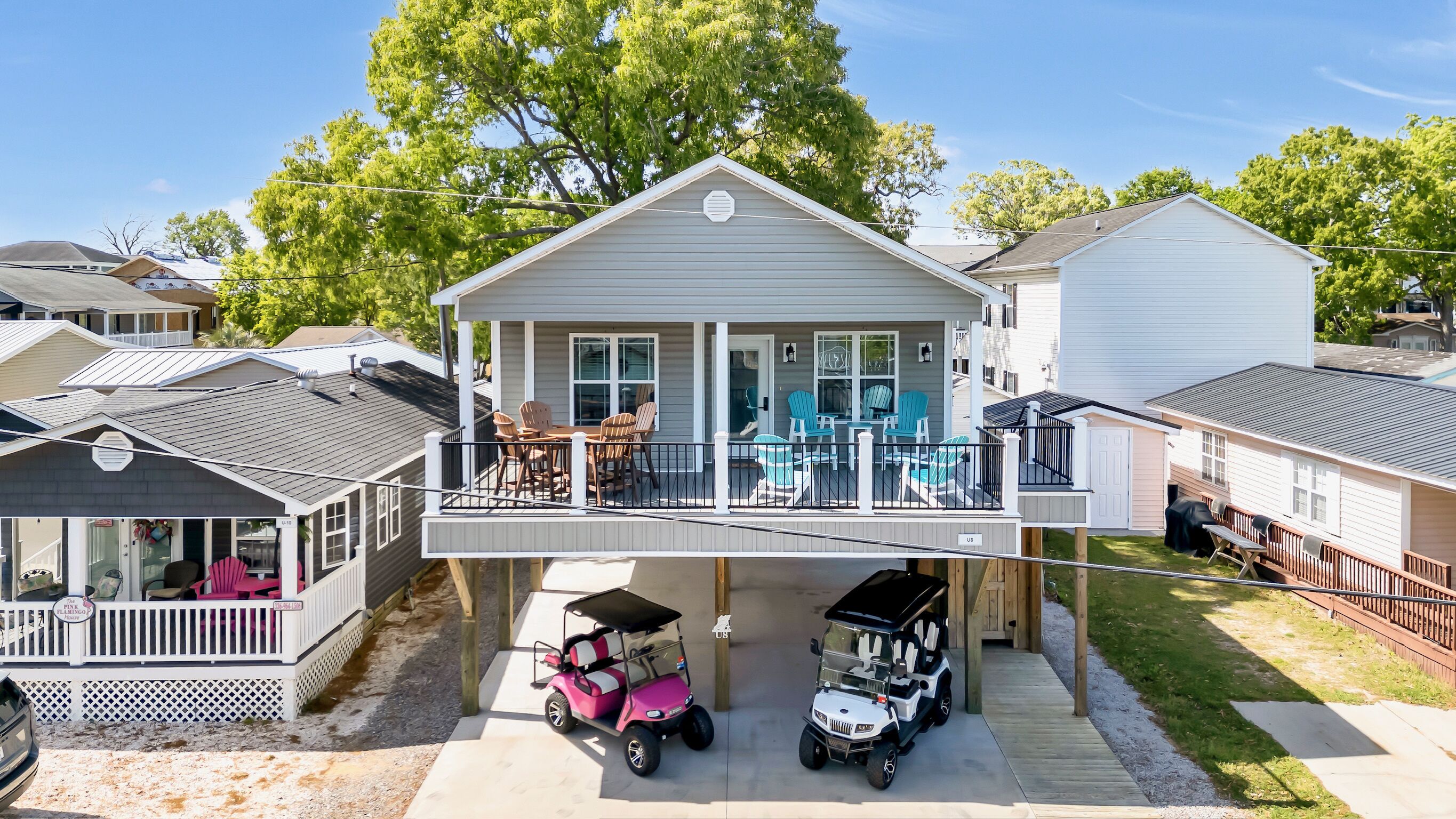 A two-story house with a balcony, a covered porch, and a garage with two golf carts.