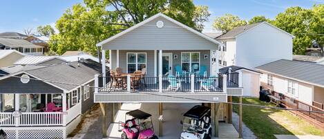 A two-story house with a balcony, a covered porch, and a garage with two golf carts.
