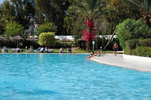 Una piscina techada, una piscina al aire libre, sombrillas