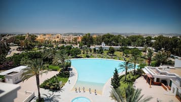 Una piscina techada, una piscina al aire libre, sombrillas