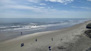 A beach with a wide sandy area, a few people walking, and a clear sky with clouds. - Sea Viewers Dream Oceanfront 5th floor ~ Kitchen Living room Bedroom  Pools Open (Daytona Beach)