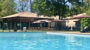 Une piscine dotée d’un espace de repos couvert et d’un bâtiment en arrière-plan.