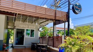A restaurant with a covered outdoor seating area, a signboard, and a blue barrel. - Baan Kenpoo Resort (Phetchaburi)