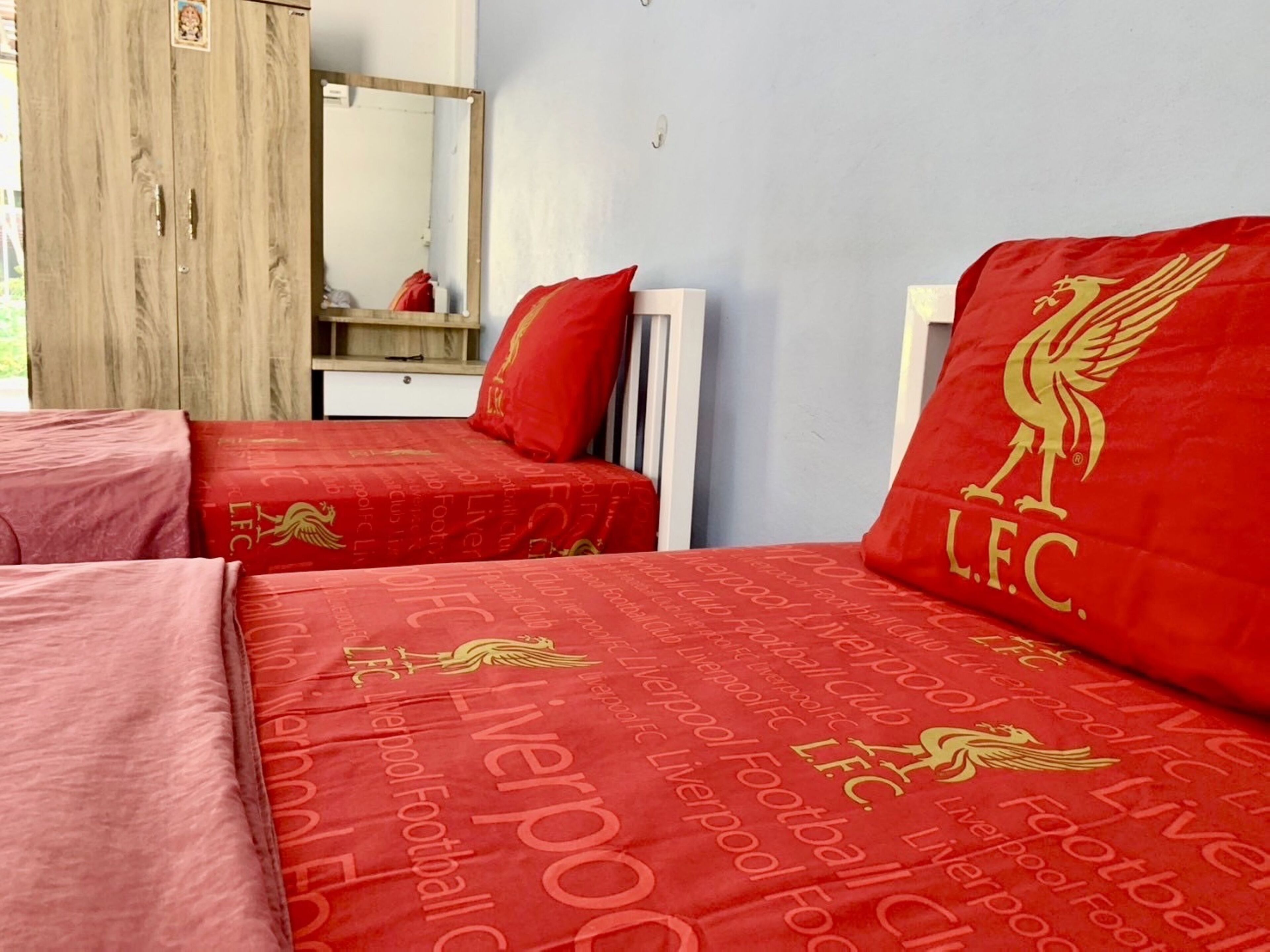 Ein Hotelzimmer mit zwei Betten, beide mit roter Bettwäsche mit dem Logo des Liverpool Fußballclubs.