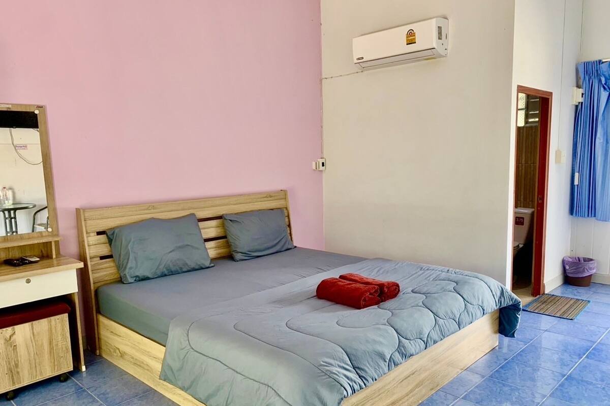 Quarto individual com cama, mesa de cabeceira, espelho e ar condicionado.