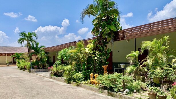 A building with a tiled roof, surrounded by lush greenery and palm trees. - Baan Kenpoo Resort (Phetchaburi)