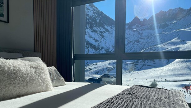 A bed with a view of a snowy mountain landscape through a large window. - Chez Tipère à La Mongie (Bagnères-de-Bigorre)