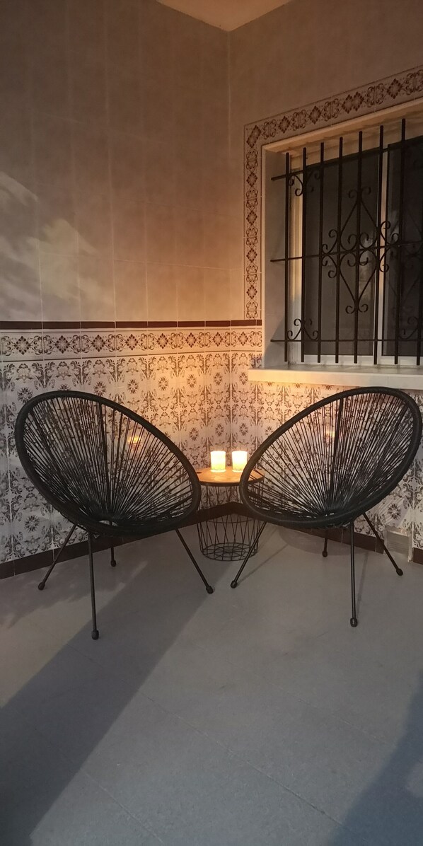 Two chairs face each other in a cozy seating area with a decorative border and ornate window.