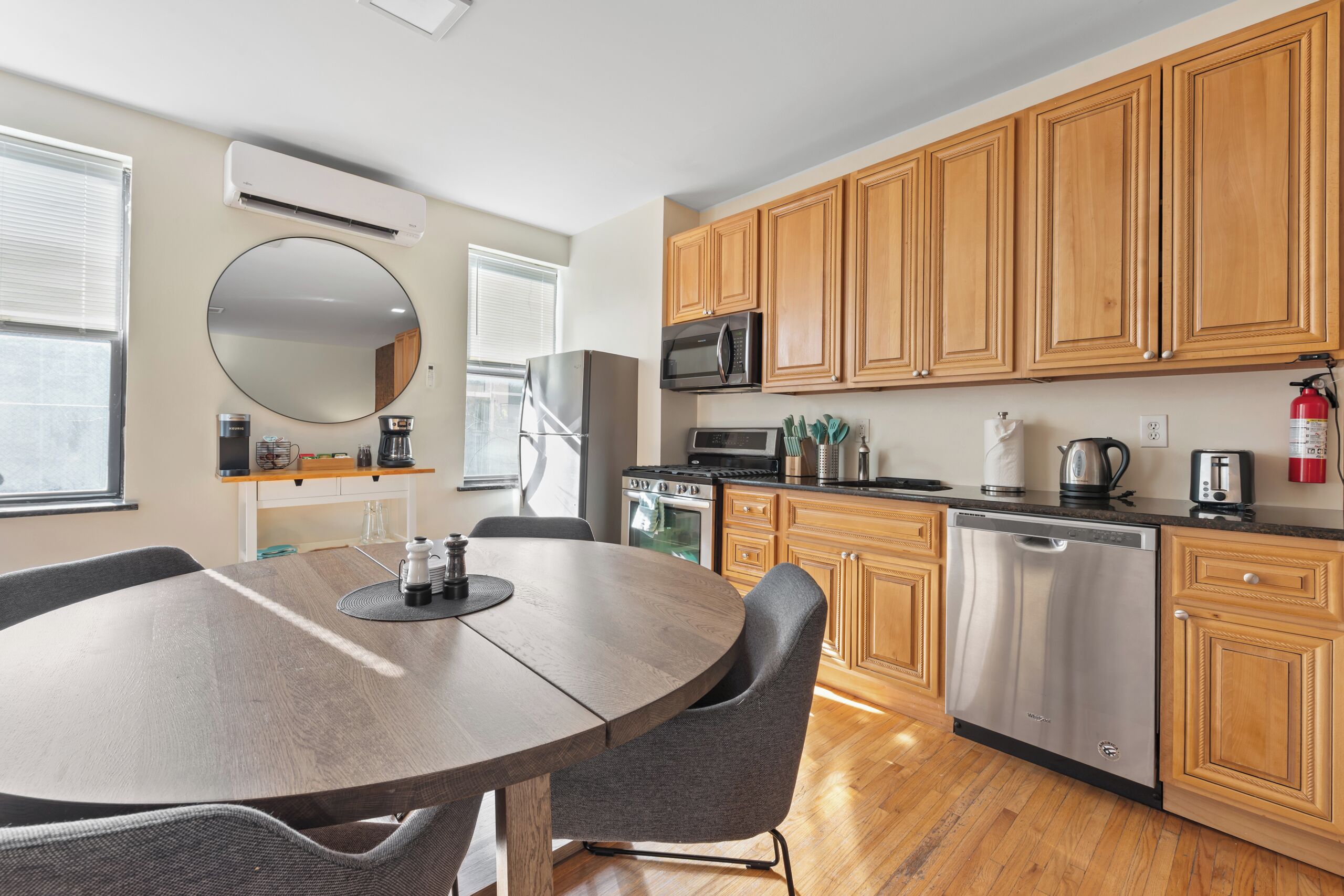 A modern kitchen with wooden cabinets, stainless steel appliances, and a round dining table with chairs.