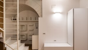 Un intérieur moderne avec un escalier, des murs blancs et des étagères intégrées.