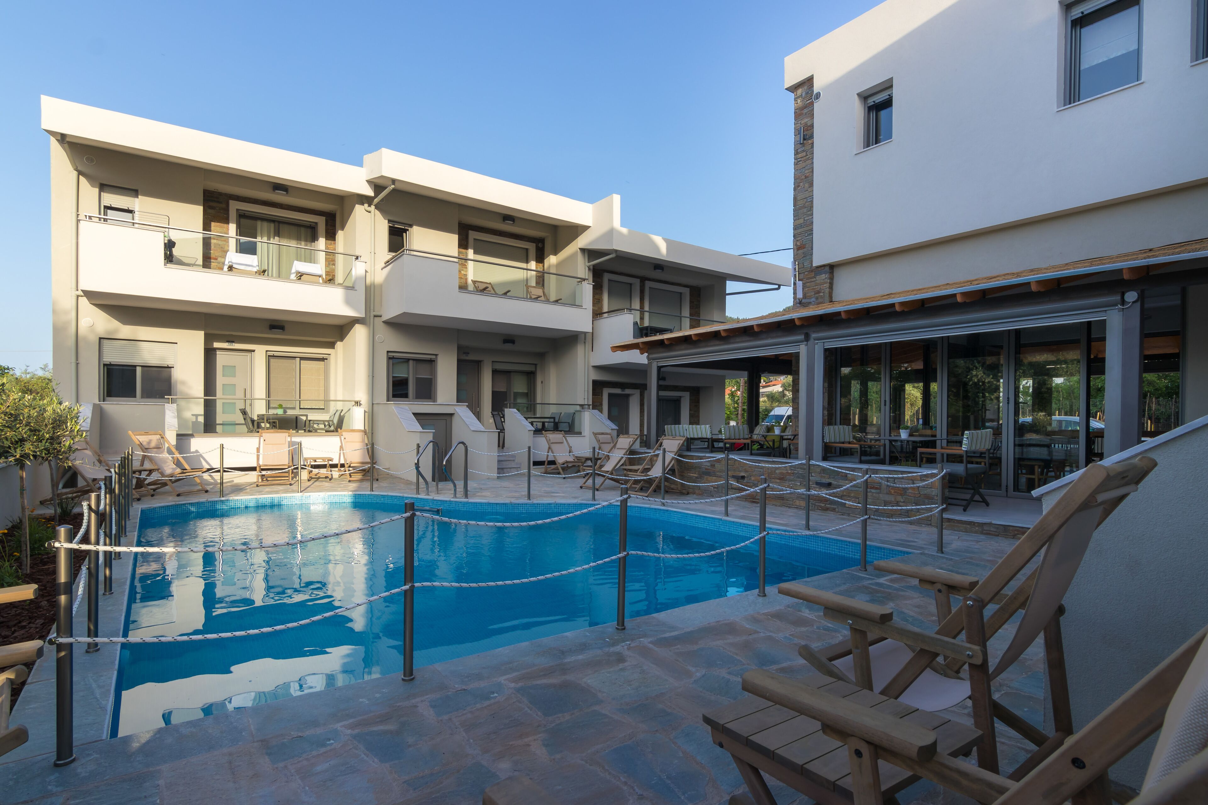 A modern building with a swimming pool, outdoor seating, and a covered area.