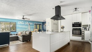 Een moderne keuken met witte kasten, een zwarte afzuigkap en een inbouwoven.
