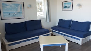 A room with two blue sofas, a white table, and two wall-mounted lamps. - Duplex vue sur le Port du Crouesty Pour 4 Personnes (Arzon)
