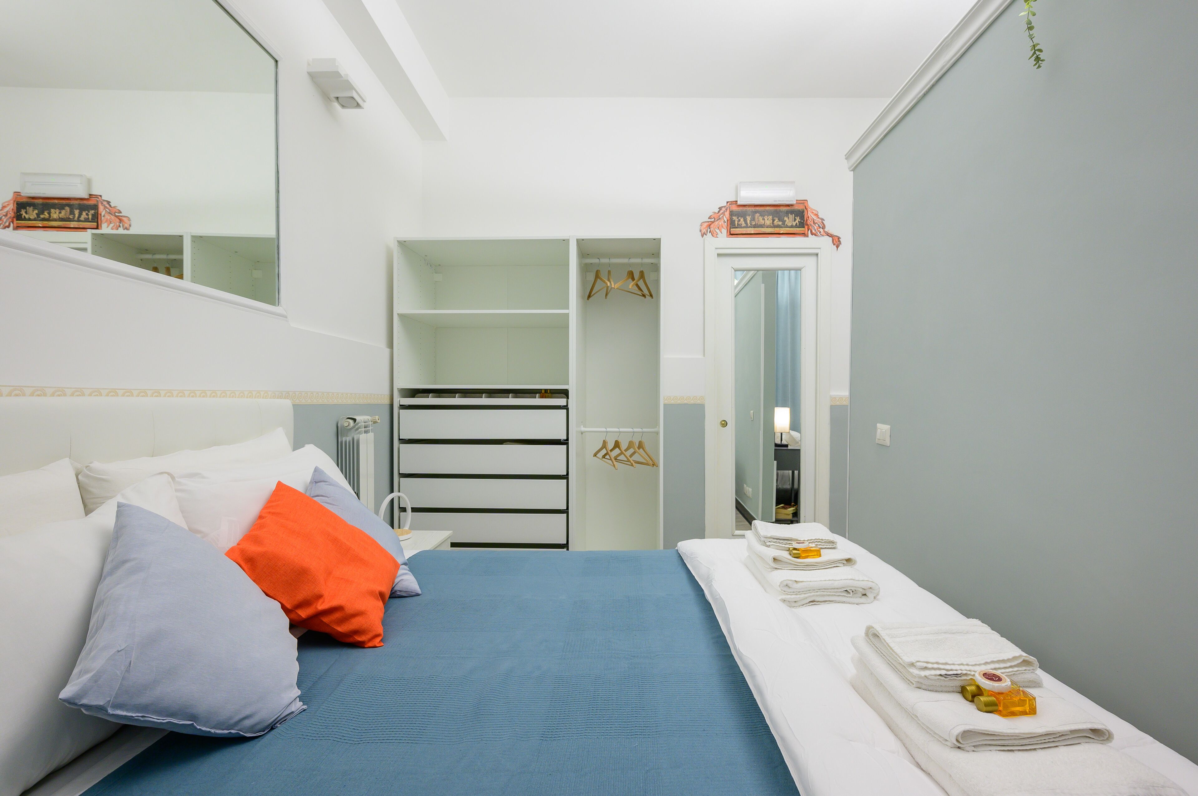 A hotel room with a bed, a walk-in closet, and a bathroom.
