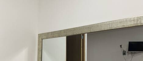 Una stanza con una panca di legno, uno specchio e un tavolino con una pianta.