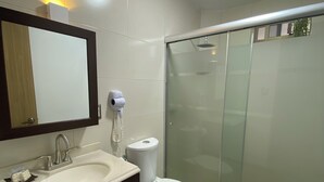 Une salle de bain moderne équipée d’un lavabo, de toilettes et d’une douche à parois en verre.