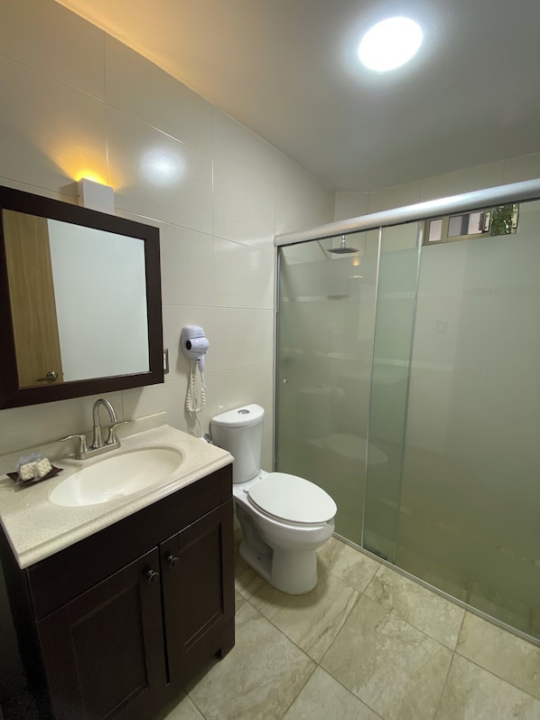 Un baño moderno con lavamanos, inodoro y cabina de ducha de vidrio.