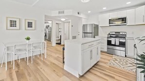 Una cocina moderna con armarios blancos, electrodomésticos de acero inoxidable y piso de madera.