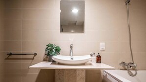 Une salle de bain équipée d’un lavabo, d’un miroir, d’une douche et d’un porte-serviettes.