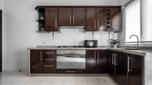 Une cuisine moderne avec des meubles en bois foncé, un four en acier inoxydable et un plan de travail en granit.