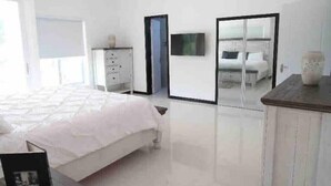 A modern bedroom with a bed, a wardrobe, a TV, and a mirror. - Quiet , pool, gated,security (kingston 19)