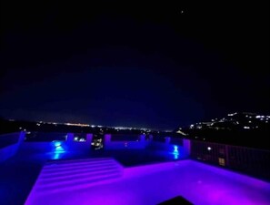 Una vista notturna di un terrazzo con una città sullo sfondo.