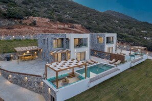 A modern villa with a pool, outdoor seating, and a stone exterior.