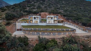 Una villa moderna con dos edificios principales, un muro de piedra y un césped bien cuidado.