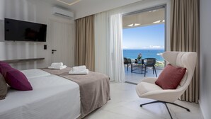 Una habitación de hotel con cama, una silla, televisor y vista al océano.