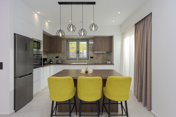 Una cocina moderna con una isla central, electrodomésticos de acero inoxidable y sillas amarillas.