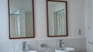 A bathroom with two sinks, wooden vanity, and large mirrors. - Rainbow Inn (St. Andrew)