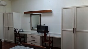 A bedroom with a bed, a desk with a chair, a TV, and wardrobe space. - Rainbow Inn (St. Andrew)