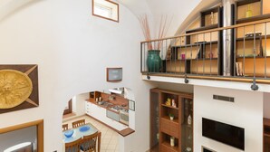 A spacious kitchen with modern appliances, a dining area with a glass table, and a living area with a flat-screen TV. - Terrazza Aragonese by Wonderful Italy (Ostuni)