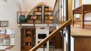 A spacious living area with a high ceiling, a wooden staircase, and a built-in bookshelf. - Terrazza Aragonese by Wonderful Italy (Ostuni)