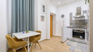 A compact kitchen with a modern stove, a small oven, and a tiled backsplash. - Visconti apartment (Roma)