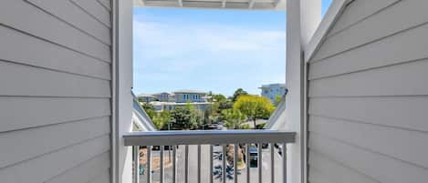 A balcony with a view of a residential area, including houses and parked cars.