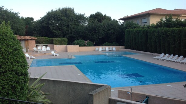 A swimming pool with white lounge chairs and a sign indicating a reserved pool for residents.